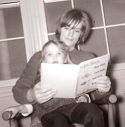 young girl in woman's lap with Dr. Seuss book being red to her. 