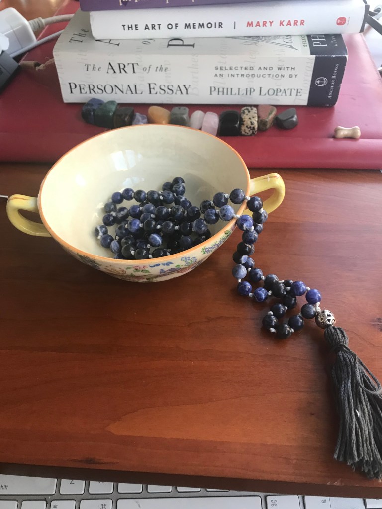 Blue mala beads in a teacup on a desk. 