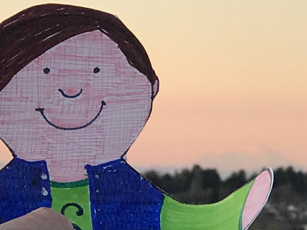 Paper cutout of boy with mountain in far distance. 
