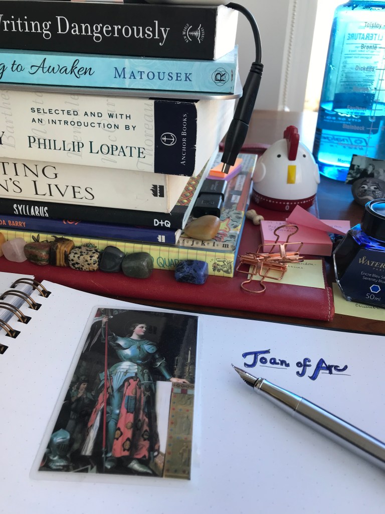 Holy Card of Joan of Arc in armor and skirt holding a staff. 