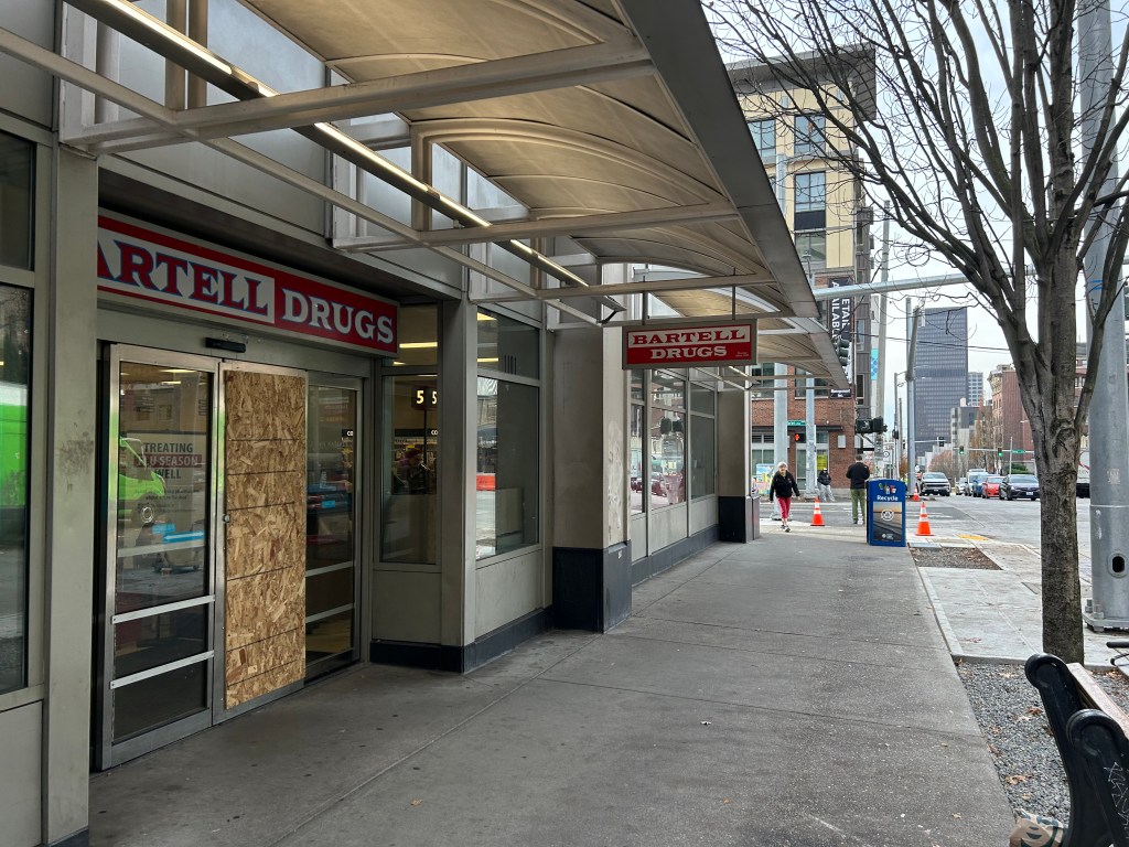 Outside of Bartell Drugs. One door covered with plywood. 