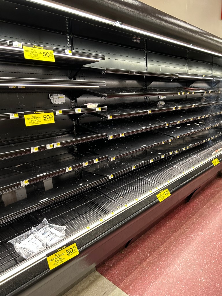 Empty refrigerated case with sale signs on it. 